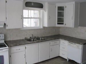 Pristine white cupboards and a granite-look counter top erase all memories of the previous kitchen's mess