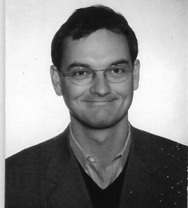 Black and white head shot of a youthful looking Richard Costley-White