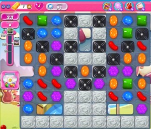 A shot of the game with various coloured shapes of candy and grey blocks of meringue that must be removed in order to complete the level.
