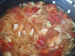 large, deep skillet with the tomato-spaghetti-chicken ingredients obviously bubbling