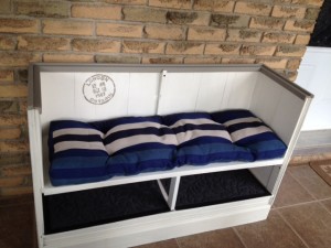 Finished bench is painted cream with grey trim and has a navy blue and cream striped cushoin along the seat. Below the seat are two shelves for storing shoes.