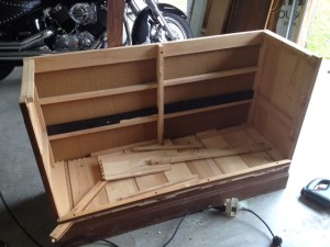 Wooden dresser with the top and front taken off and pieces of wood placed on what will become the low shelf of the bench