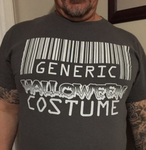 Derek wears a dark grey T shirt with a white bar code, and Generic Halloween Costume in white lettering