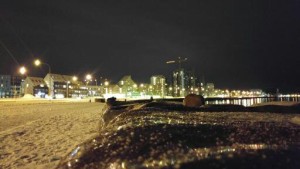 the rocky shore at the bottom of the city of Reykjavik with city lights in the background
