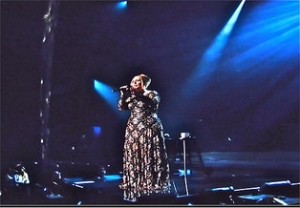 Adele in a flowery gown, singing in concert