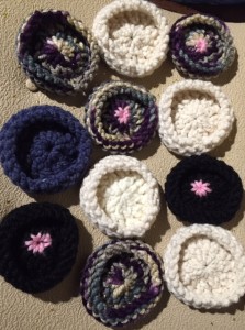 a collection of knitted coasters in a variety of colours