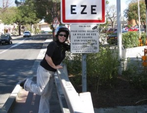 I'm wearing a helmet and have my arm around the sign for the town of Eze, France