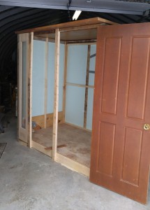 framed walls are up, a door is ready to be installed and a tall, thin window can be seen on the far left