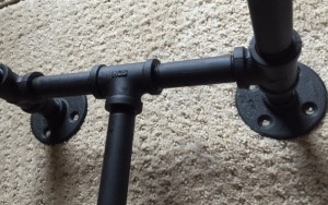 close-up of flat black pipe that makes up the legs of the table.