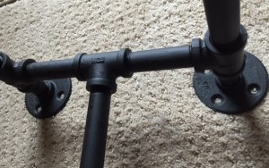 close-up of flat black pipe that makes up the legs of the table. 