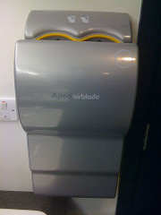 long, grey dryer affixed to a wall with hand-shaped openings at the top where you insert your wet hands, fingers first
