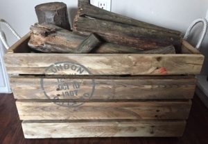 unpainted crate with London postal stamp stencil and rope handles, full of firewood and kindling