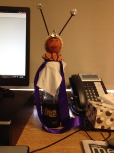 A creature on my desk has an orange for a head, sits on a glass water bottle with a napkin as a cape, and all sorts of things embellishing him including stir-sticks with crushed foil stuck in his head for antennas