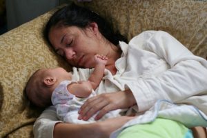 Young Mom and her baby daughter asleep on a couch