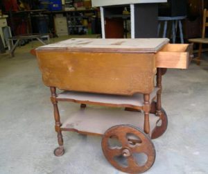 antique tea trolley with castors on the front legs and large wheels on the back
