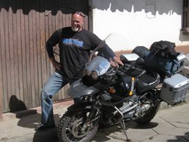 Kevin posing with his motorcycle and smiling widely