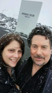 Derek and I smiling in the falling snow, up close, with the Blue Lagoon sign in the background and my gaping tooth hole quite obvious!