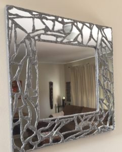 square mirror has mosaic of mirror pieces as its frame and they appear held together by lead, like a piece of stained glass