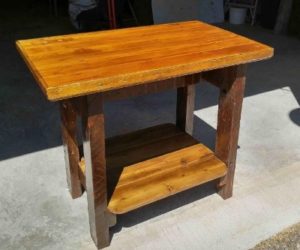 table that looks like a too-small dining table, made of 100-year-old fir legs with a pallet-wood shelf on the bottom and a piece of a vintage door on top, all stained dark