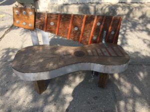Bench made to look like a guitar with the body as the seat and the neck as the backrest