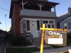 sold sign in front of old brick house with freshly painted white balcony and front door