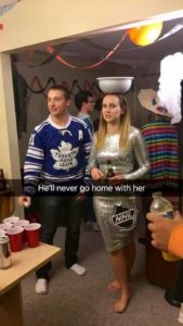 Man dressed up as a Maple Leafs player with a woman dressed as the Stanley Cup. Captioned: He'll never go home with her!