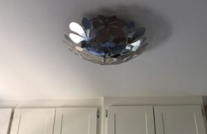 silver toned bowl of giant, flat flowers on ceiling as a light fixture