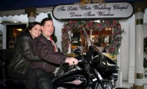 Derek and I on a black Harley in front of a sign that reds the Little White Wedding Chapel Drive Thru Window