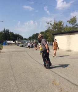 rider on two-wheeled scooter thing, about to make a sharp turn in front of me