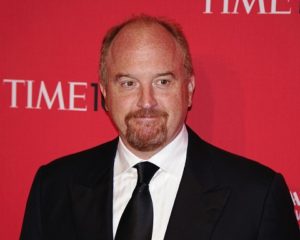 Louis CK with a half smile, in front of a Time Magazine backdrop