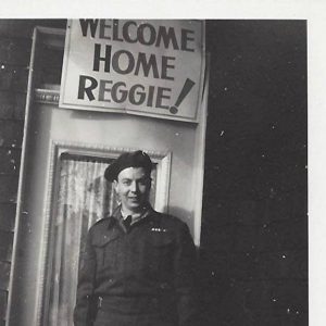 Derek's Dad in uniform under a sign that reads Welcome Home Reggie!