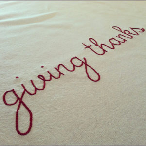 giving thanks written in lower case red script across a canvas