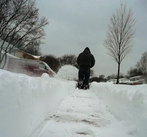 Shot of a cleared sideway as a person with a snowblower works up ahead