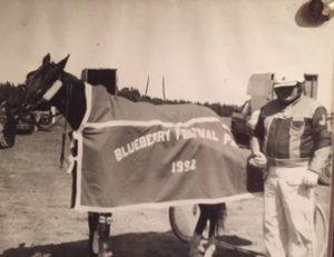 My Dad in his racing suit and helmet standing with his horse, Accumulator, in the winner's circle after winning a race on PEI in 1992