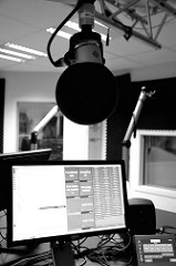 Closeup of a microphone suspended over an on-air computer in a radio broadcast studio