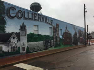 Collierville mural painted on the side of a brick building shows a church, silos, and other old buildings