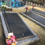 Elvis' grave in the forefront with matching slabs of granite and large plaques in the background, makring the graves of his parents