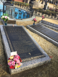 Elvis' grave in the forefront with matching slabs of granite and large plaques in the background, makring the graves of his parents