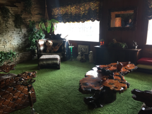 The infamous jungle room has turf-like green carpet, a huge chair and ottoman coverd in some kind of fur, as well as big, laquered wood tables