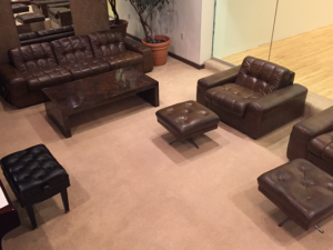 Shot from overhead, the lounge features manly, brown leather couches and chairs with a piano along one wall