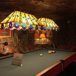 Two large Tiffany lamps over a huge pool table. The ceiling and walls are covered in pleated fabric of rust, yellow, green and gold.