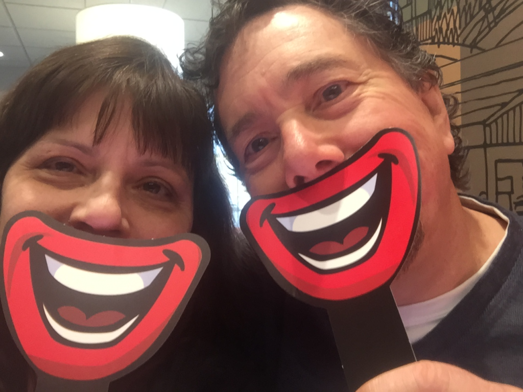 Derek and I holding cardboard cartoon smiles up to our mouths in a McDonald's