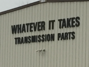 Sign on a huge metal building reads Whatever It Takes Transmission Parts