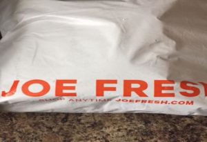 Unopened white delivery bag sits on the kitchen counter with the words Joe Fresh in bold orange