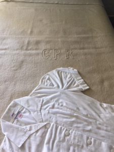 cream-coloured wool blanket with CPR embroidered in the centre, and a white CPR waitress uniform laid beside it