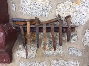 a collection of rusted railway spikes hangs like a sculpture near the entrance to the station