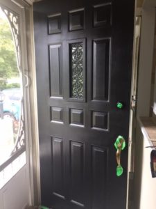 door is now a low-lustre black. Green painters tape still surrounds the lock and handle