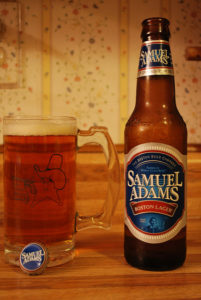 A bottle of Samuel Adams beside a cold glass full of beer