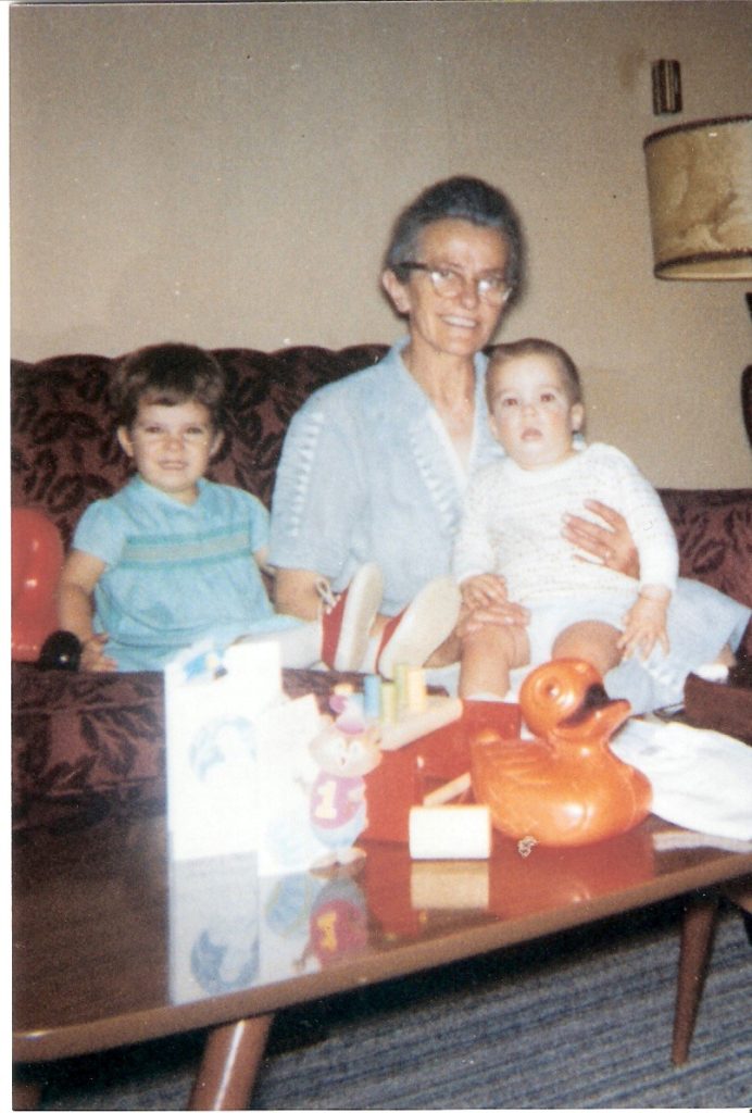 picture from the 70s of our ancient, birdlike Grandma with baby Kevin on her lap and me, a toddler, sitting beside her. All are smiling. 