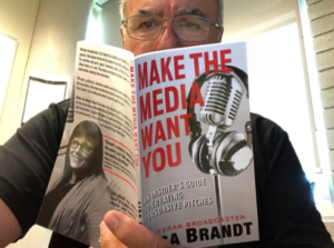 Man looking very serious holding up the book as if he's reading it